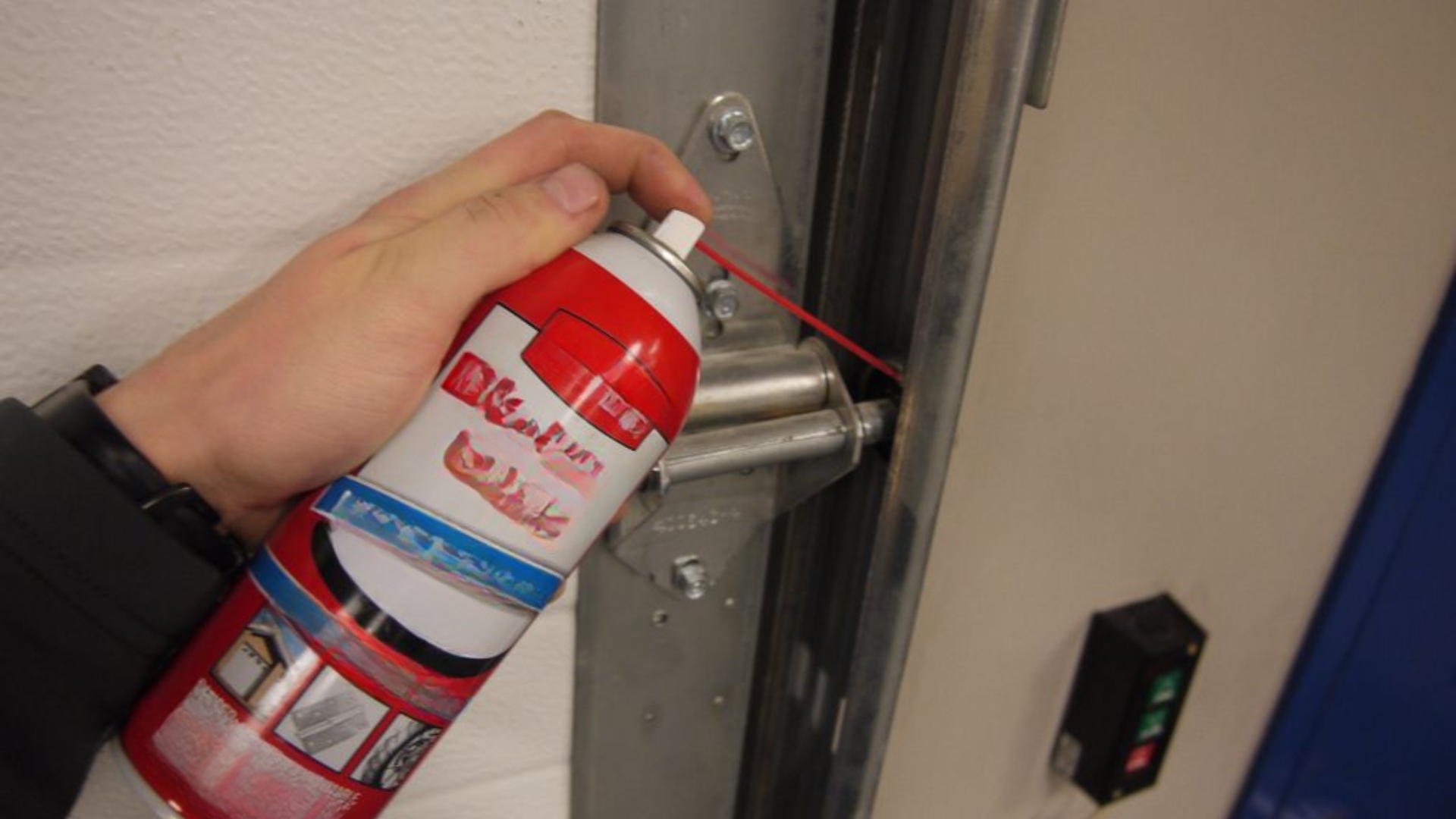 A technician applying garage door lubricant on garage door roller