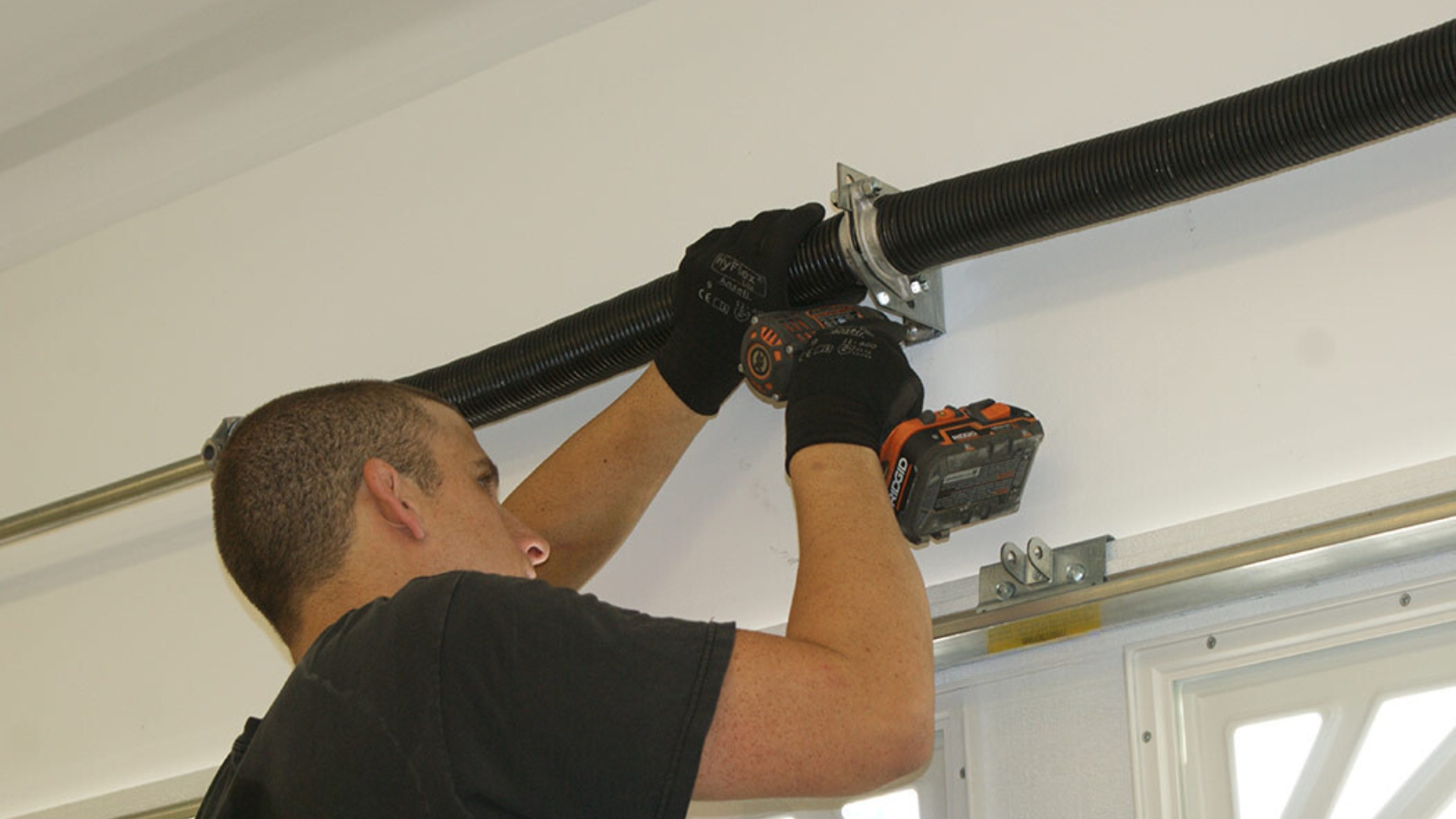 A garage door expert adjusting the torsion springs above the door