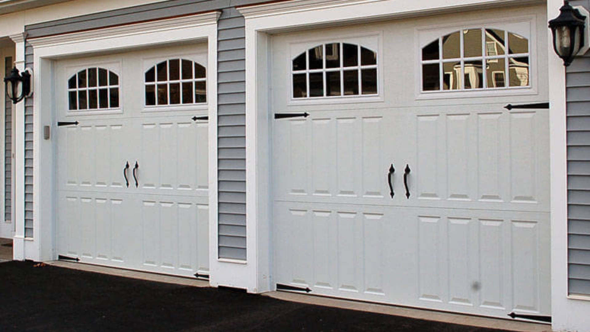 Custom garage door fitting with arched windows and intricate black hardware.