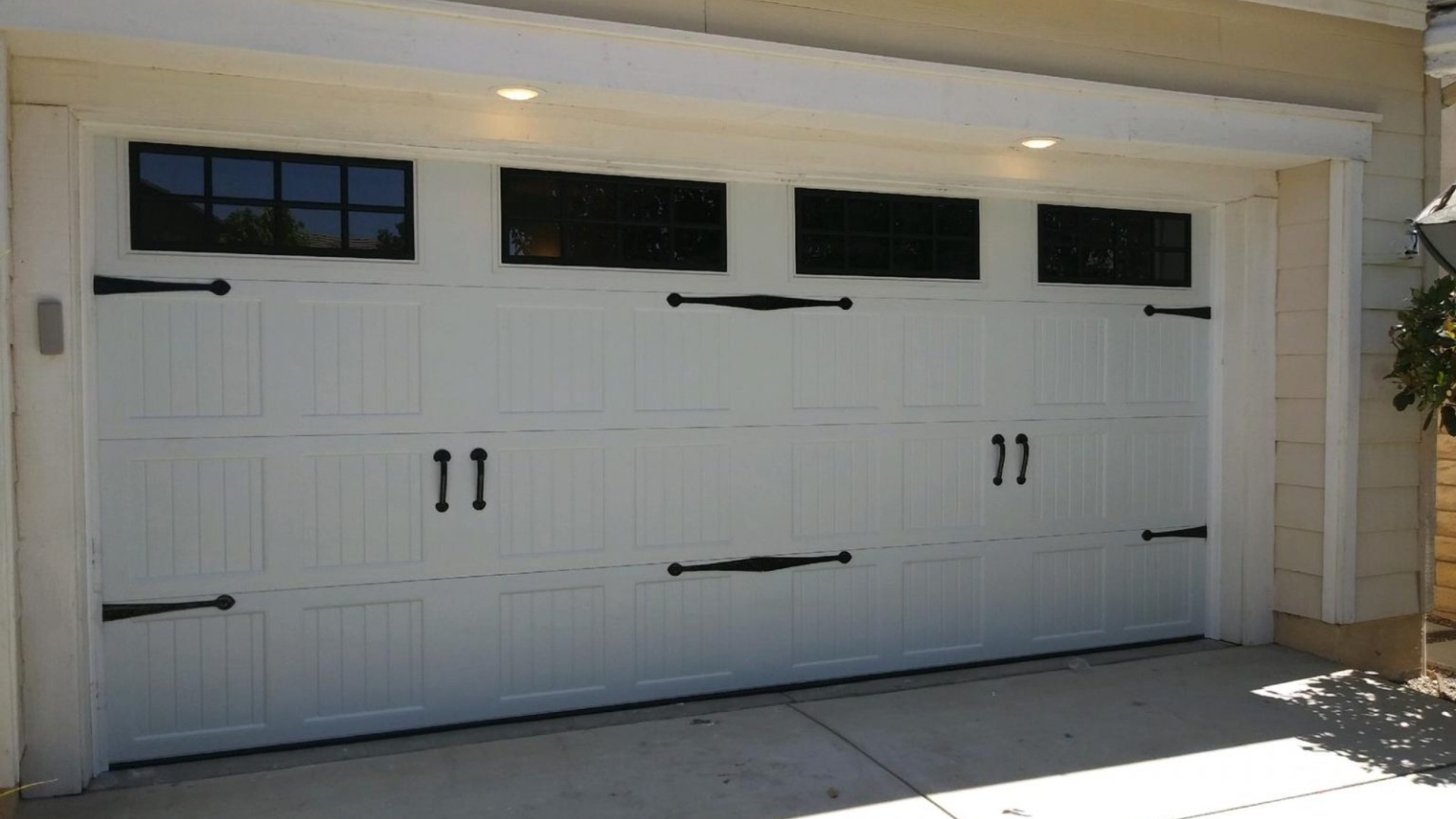 White paneled garage door fitting with decorative black hardware for a sleek look.