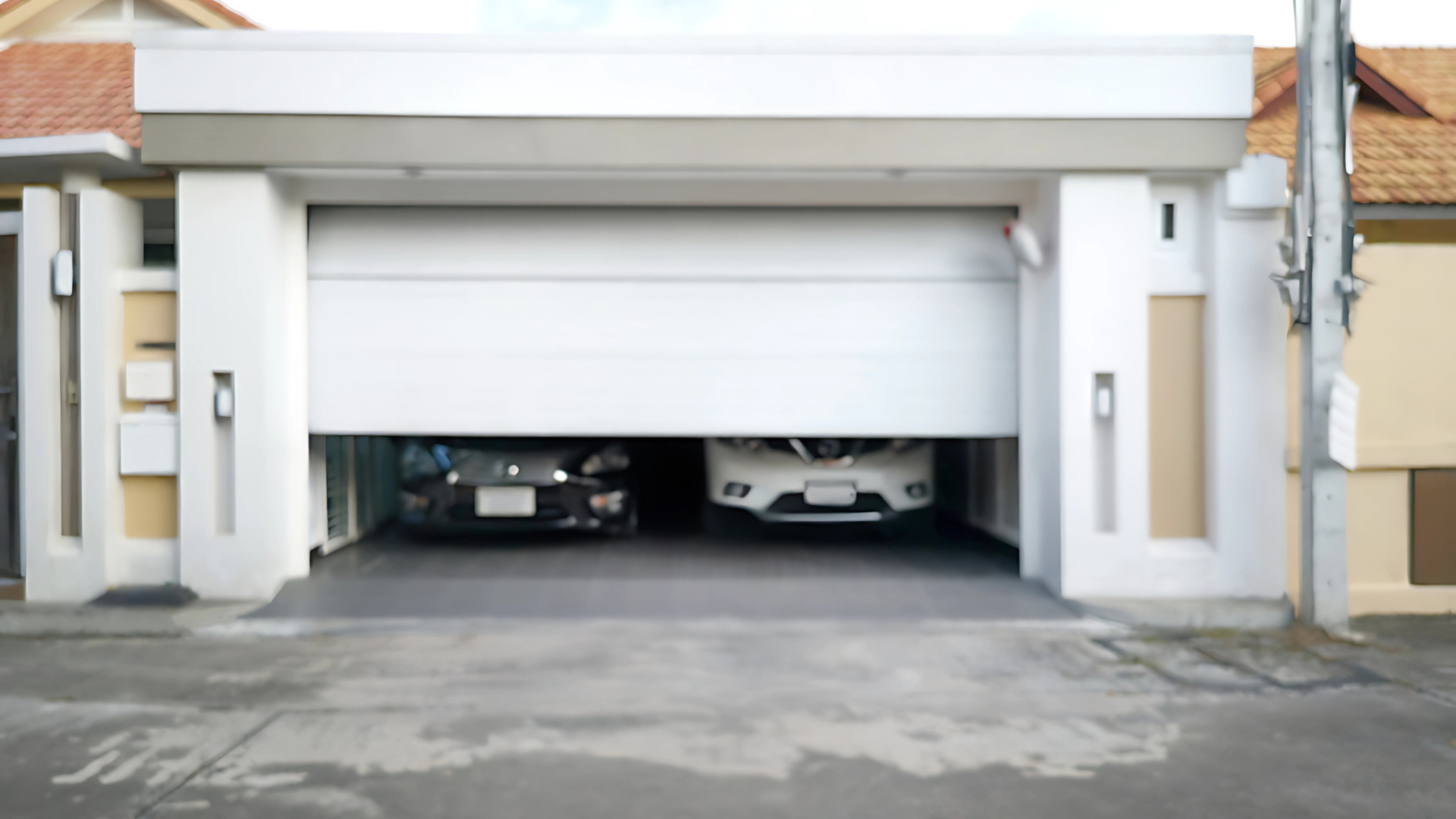 Two parked cars behind a half-open stuck garage door, requiring sensor replacement.