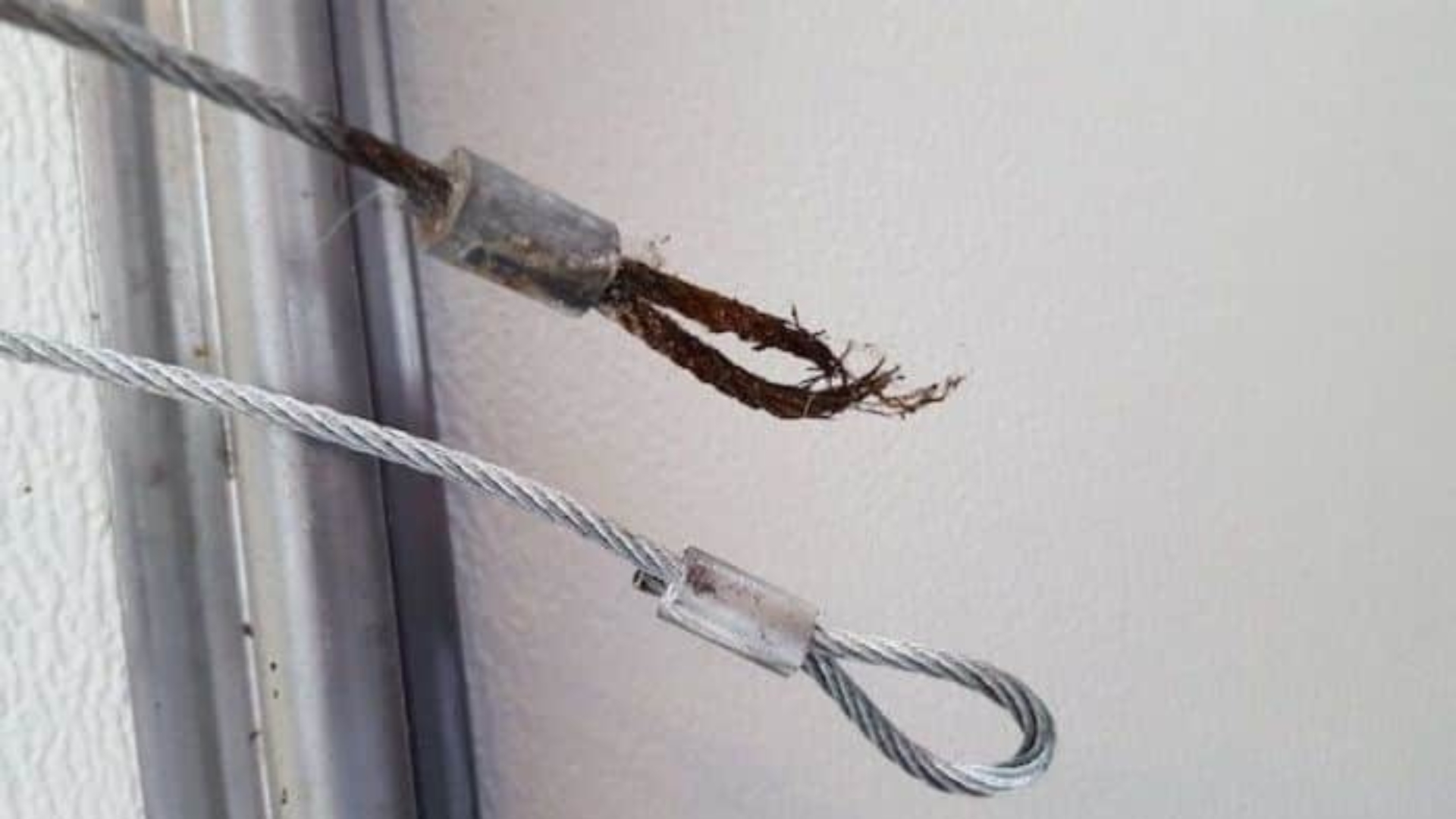 Damaged and rusted garage door cable showing visible breaks.