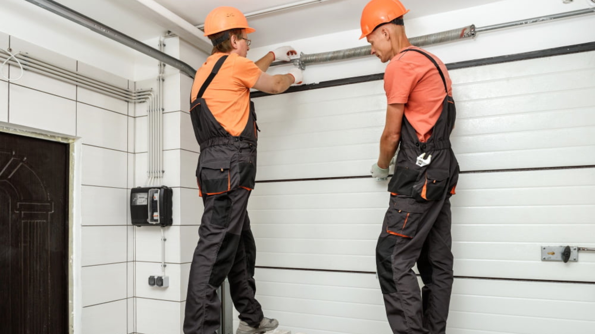 Two garage door experts installing a sectional garage door.