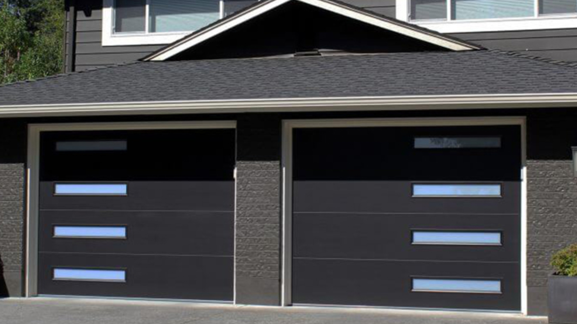 A sleek black flush panel garage door with modern glass inserts.