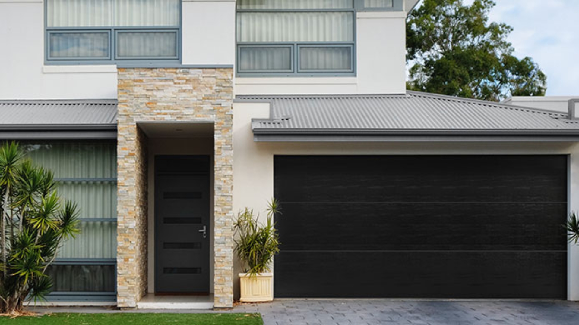 Modern home entrance with a sleek black flush panel garage door.